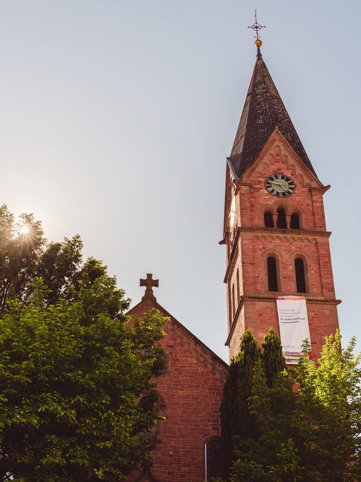 Der schlanke Sandsteinturm der evangelischen Dorfkirche Bammental mit Spitzhelm – Wahrzeichen am Kirchplatz.