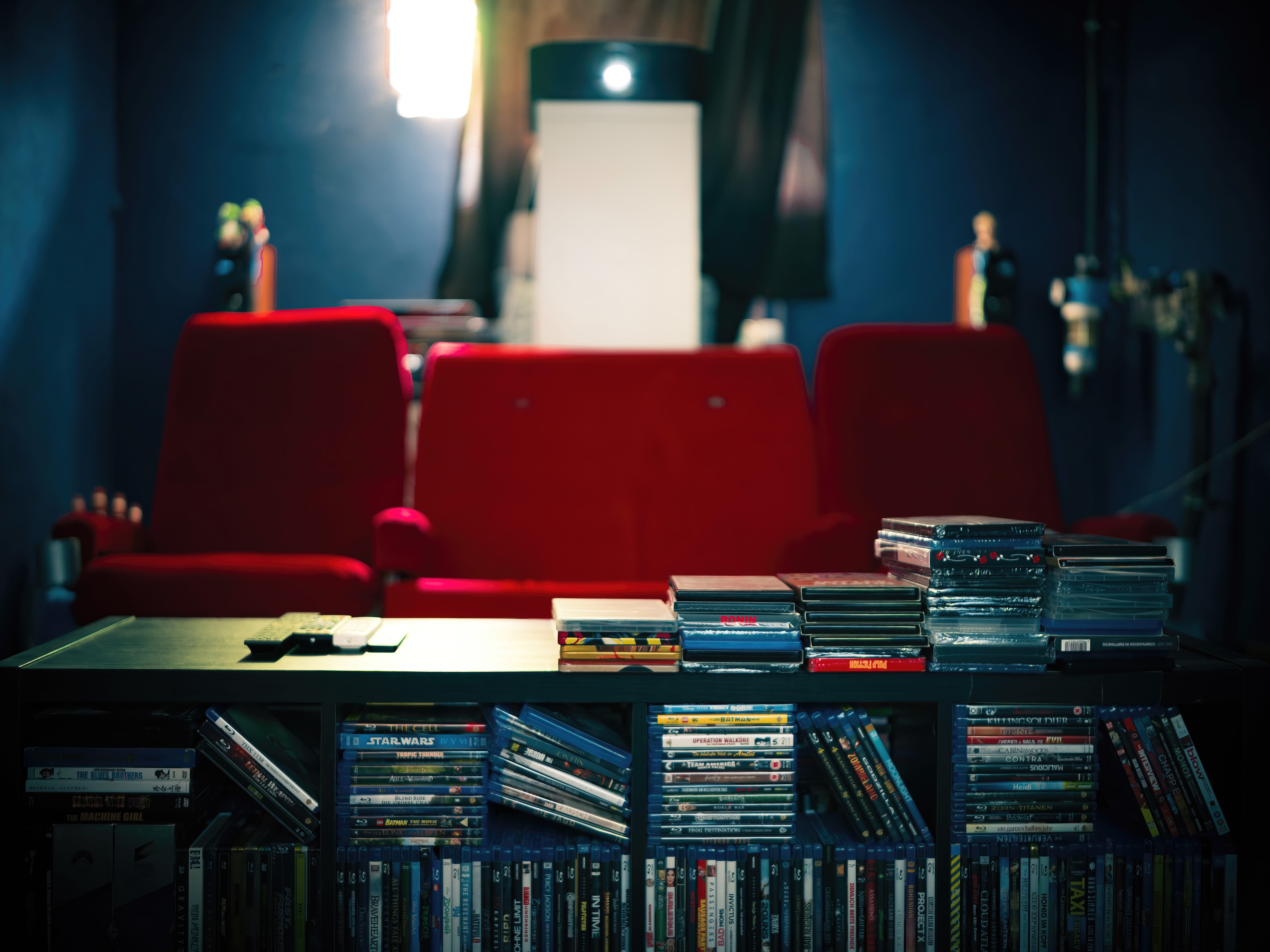 Rote Kinosessel im privaten Heimkino mit dunkelblauen Wänden und JVC Beamer für authentisches Kino-Feeling.
