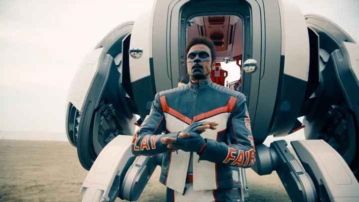 Filmstill aus Superman (2025): Hightech-Shuttle am Strand, uniformierter Held mit schwebenden Drohnen – Sci-Fi-Look des DC-Reboots von James Gunn