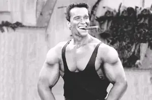 Arnold Schwarzenegger flexing muscles and smoking a cigar during bodybuilding era